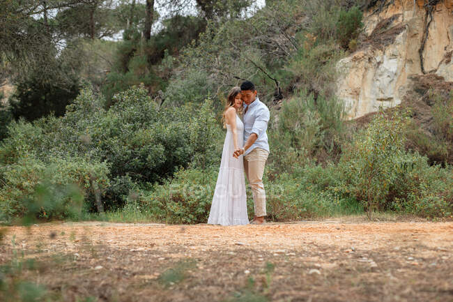 Mariée et marié divers embrassant tout en se tenant dans la forêt le jour du mariage — Photo de stock