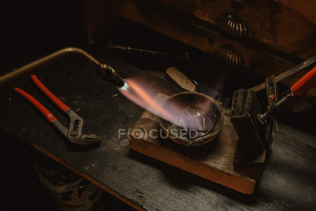 Unbekannter Goldschmied schmilzt in Werkstatt neben Werkbank Metall für Schmuck mit Blaslampe — Stockfoto