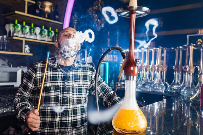 Uomo che fuma narghilè tradizionale in un night club — Foto stock