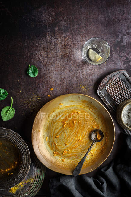 Vista superior del plato vacío sucio con cuchara después de comer garbanzos comida al curry en la mesa con utensilios de cocina - foto de stock