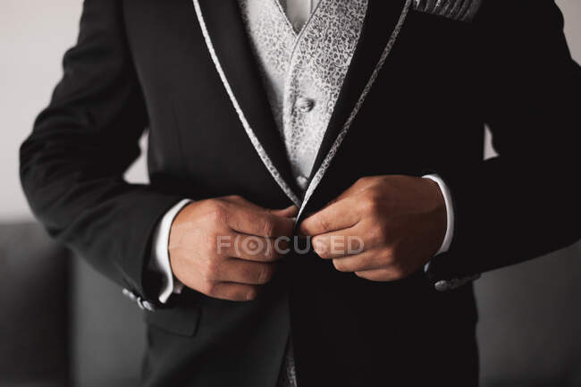 Crop unkenntlich Mann knöpft stilvolle elegante schwarze Bräutigam Jacke während der Vorbereitung für die Hochzeitszeremonie — Stockfoto