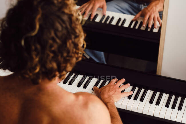 From above of anonymous male musician playing melody on piano while rehearsing at home — Stock Photo