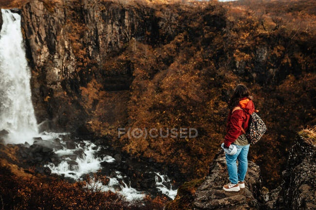 Mulher em óculos entre terras selvagens com cachoeira — Fotografia de Stock