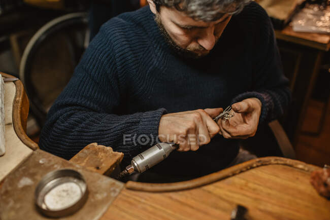 Jeweler using professional polishing machine on workbench while making metal ring in workshop — Stock Photo