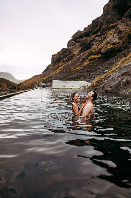 Paar lacht im Wasser zwischen Bergen — Stockfoto