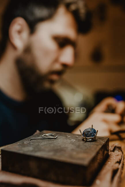 Bijoutier méconnaissable utilisant une machine de polissage professionnelle sur un établi tout en faisant une bague en métal dans un atelier — Photo de stock