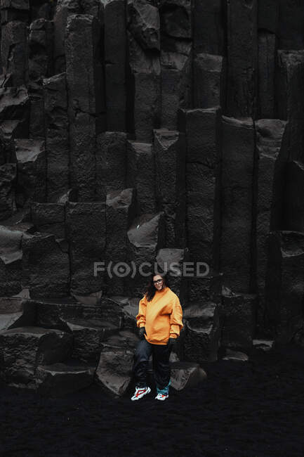 Junger Tourist posiert in Brille nahe hoher schwarzer Steinmauer — Stockfoto