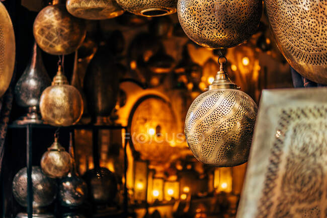 Golden metal rounded ornamental lamps with patterns in traditional street shop in Morocco — Stock Photo