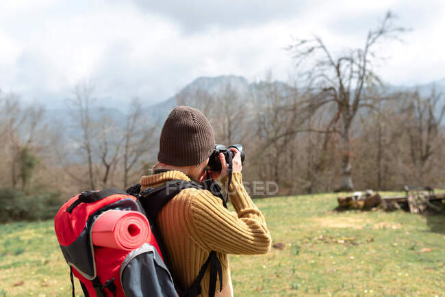 Rückansicht einer anonymen Backpackerin, die während der Reise bergige Landschaft fotografiert — Stockfoto