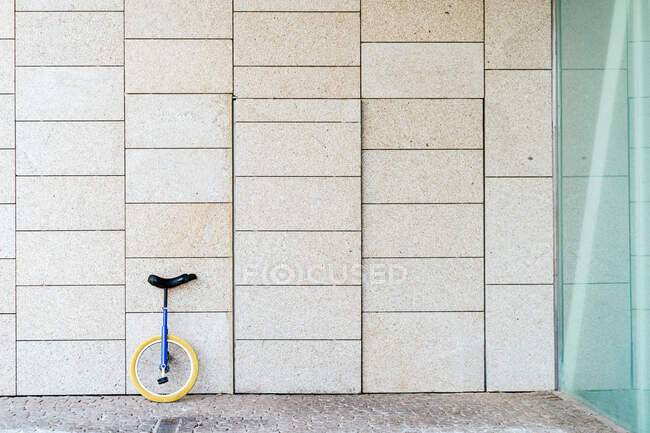 Unicycle moderno estacionado perto da parede de pedra do edifício contemporâneo com projeto geométrico na cidade — Fotografia de Stock