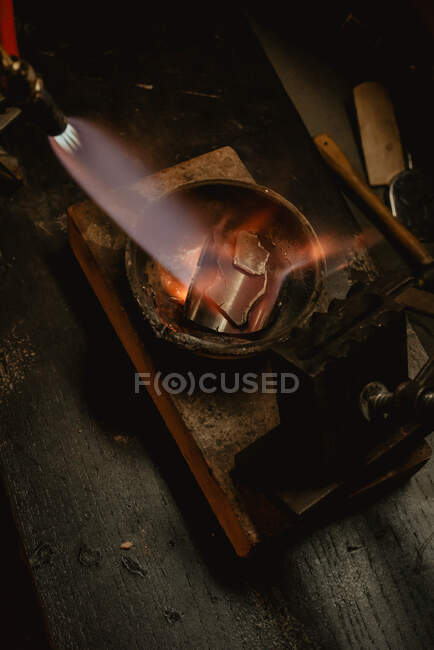 Orfèvre méconnaissable fondre le métal pour les bijoux avec chalumeau tout en se tenant près de l'établi dans l'atelier — Photo de stock