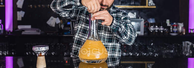 Обрізаний невпізнаваний чоловік готує великий скляний традиційний кальян у нічному клубі — стокове фото