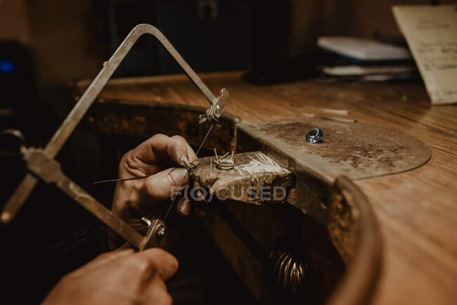 Ourives anônimos corte de metal com serra ao fazer jóias em oficina — Fotografia de Stock