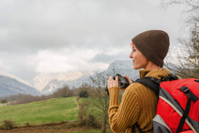 Side view of female backpacker taking picture of mountainous landscape during travel — Stock Photo