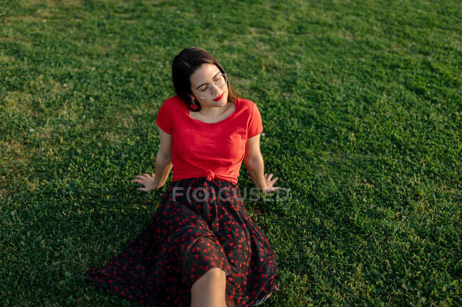Tranquilo fêmea sentado na grama no prado no parque e desfrutar do pôr do sol no verão — Fotografia de Stock
