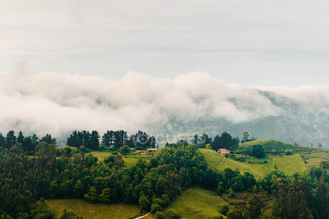 Nuvens cinzentas grossas flutuando no céu sobre colinas verdes no dia maçante no campo — Fotografia de Stock