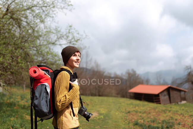 Вид сбоку на застенчивую женщину с рюкзаком, гуляющую в горах и отводящую взгляд — стоковое фото