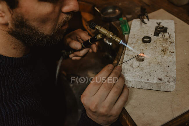 Анонімні чоловічі ювеліри використовують файл для формування металевого кільця на верстаті в майстерні — стокове фото