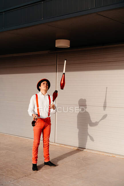Опытный молодой артист цирка жонглирует клубом на современном здании — стоковое фото