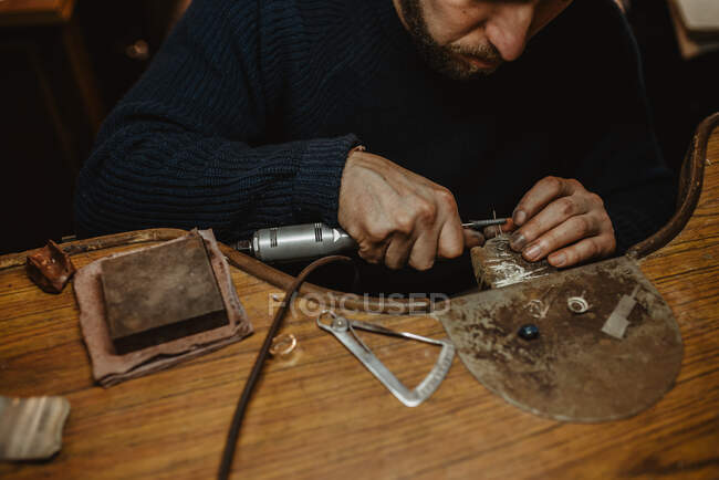 Bijoutier utilisant une machine de polissage professionnelle sur établi tout en faisant une bague en métal dans l'atelier — Photo de stock