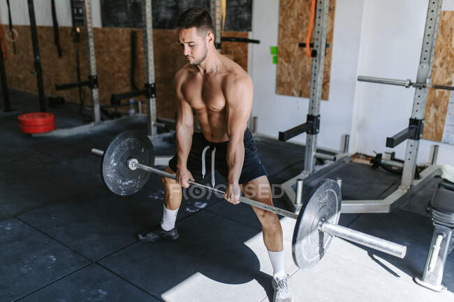 Сильний спортсмен чоловічої статі робить мертвий підйом з важким барбелом під час тренувань у спортзалі — стокове фото