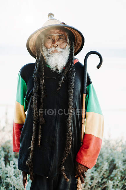 Retrato de rastafari viejo con rastas mirando a la cámara en la naturaleza con fondo blanco - foto de stock