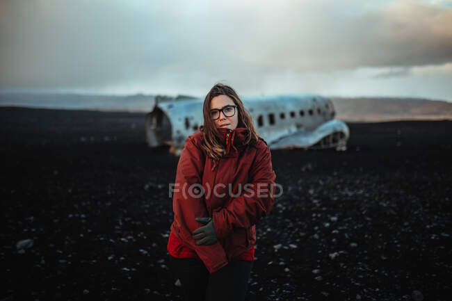 Young tourist standing on wrecked aircraft between deserted lands and blue sky — Stock Photo