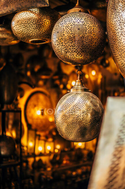 Lâmpadas ornamentais arredondadas de metal dourado com padrões na loja de rua tradicional em Marrocos — Fotografia de Stock