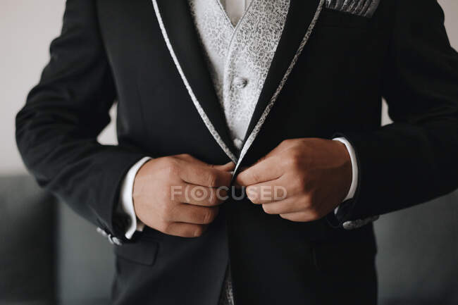 Обрізати невпізнаваний чоловік натискання стильний елегантний чорний піджак нареченого під час підготовки до весільної церемонії — стокове фото