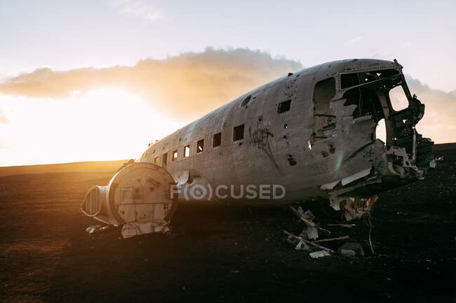 Wrecked aircraft between black deserted lands and blue sky with sunshine — Stock Photo