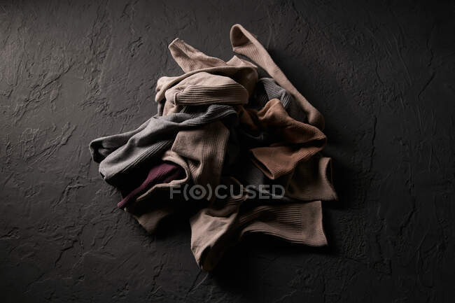 Vista superior del bozal creativo de perro hecho de prendas arrugadas surtidos y telas sobre fondo negro - foto de stock