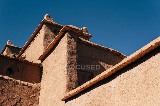 Desde abajo de envejecido edificio de piedra con cielo azul claro sobre fondo en Marruecos - foto de stock
