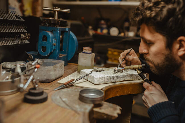 Oreficeria con fiamma ossidrica per riscaldare minuscoli ornamenti metallici mentre si realizzano gioielli sul banco da lavoro — Foto stock