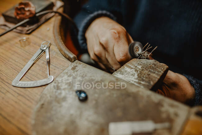 Ювелир с помощью профессиональной полировальной машины на рабочем столе при изготовлении металлического кольца в мастерской — стоковое фото
