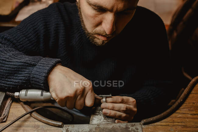 Mãos de ourives macho usando ferramenta manual para moldar anel de metal na oficina — Fotografia de Stock