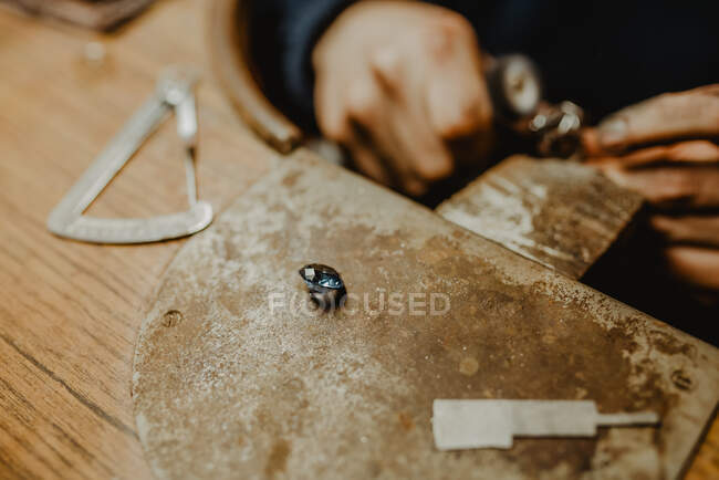 Jeweler using professional polishing machine on workbench while making metal ring in workshop — Stock Photo