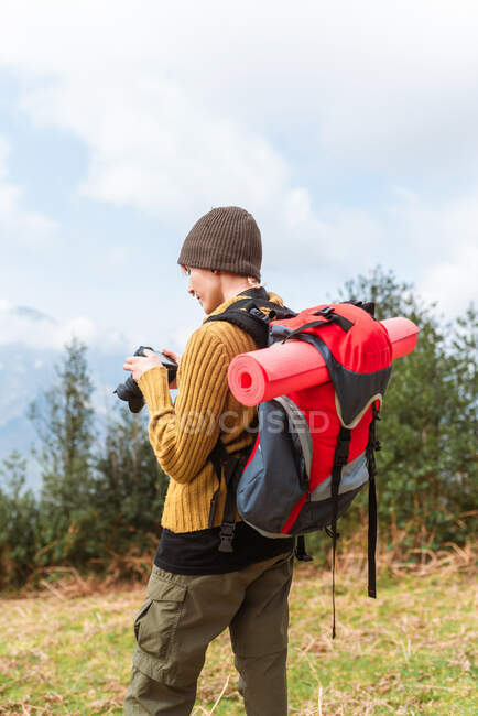 Seitenansicht einer Backpackerin beim Fotografieren der bergigen Landschaft während der Reise — Stockfoto