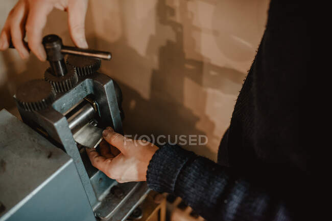 Неузнаваемый ювелир, использующий металлический орнамент на машине во время изготовления кольца в мастерской — стоковое фото