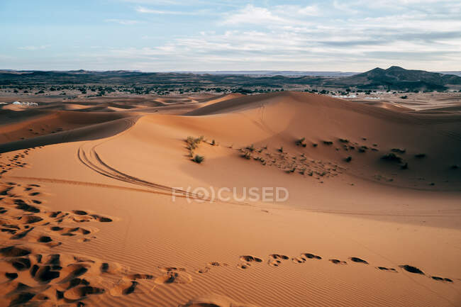 Dall'alto del deserto vuoto colorato con grandi dune sotto il cielo blu nuvoloso in Marocco — Foto stock