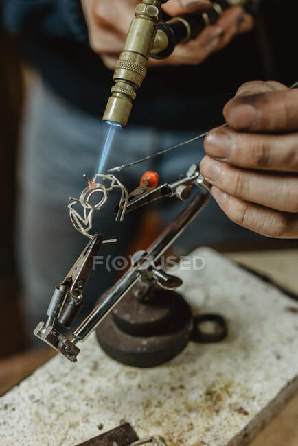 Руки анонімного чоловічого золотошукача з використанням ручного інструменту для формування металевого кільця в майстерні — стокове фото