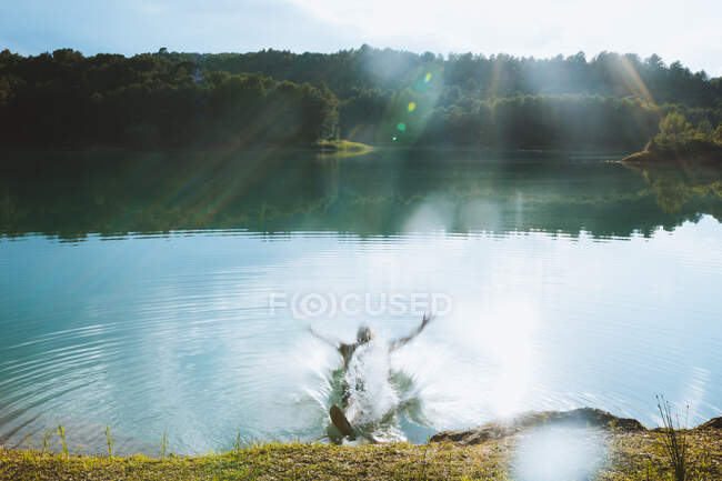 Unrecognizable man falling in lake on sunny day in dolomites in Italy — Stock Photo