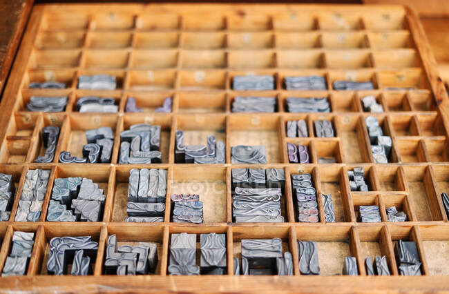 Conjunto de símbolos de tipografía de metal y adornan imágenes colocadas en caja de madera en tipografía - foto de stock