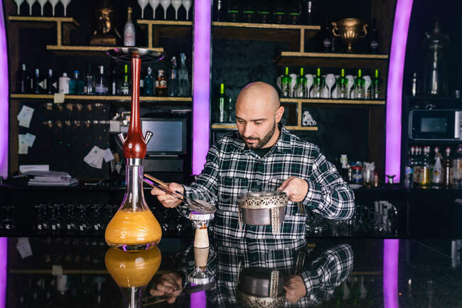 Uomo preparare un grande vetro narghilè tradizionale in un night club — Foto stock