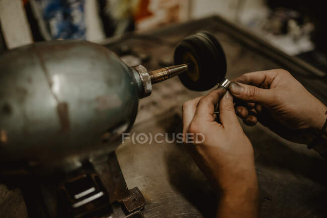 Mãos de ourives masculinos anônimos usando ferramenta manual para moldar anel de metal na oficina — Fotografia de Stock