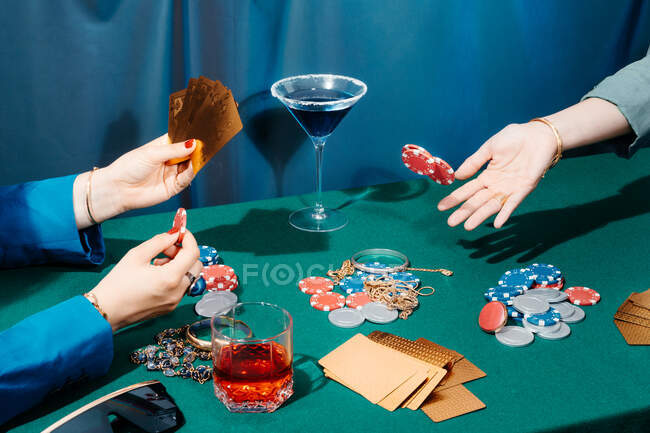 Обрізати невпізнаваних друзів, які сидять за зеленим столом з картами та покерними фішками під час азартних ігор — стокове фото