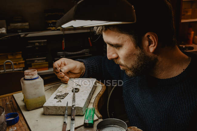Orafo maschio utilizzando strumento manuale per modellare anello metallico in officina — Foto stock