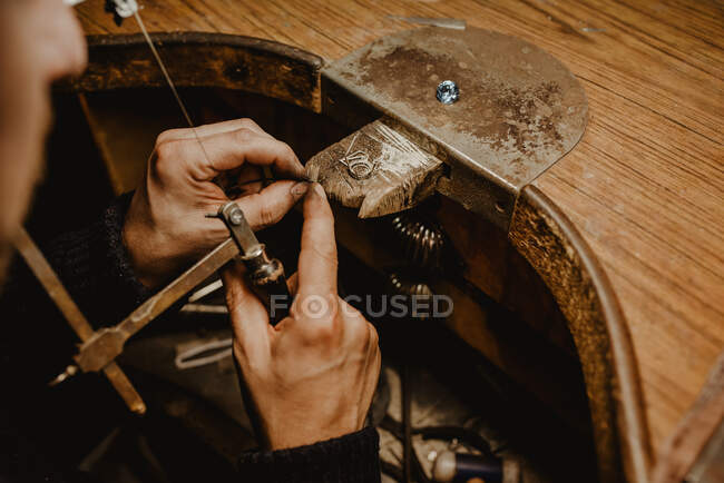 Goldsmith corte de metal con sierra durante la fabricación de joyas en taller - foto de stock