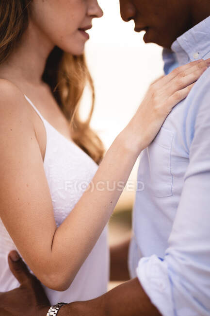 Side view of crop young multiethnic bride and groom embracing tenderly while having romantic moments together — Stock Photo