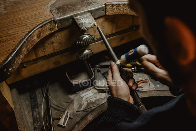 Anónimo orfebre martillando y expandiendo anillo en blanco en palo de metal mientras trabajaba en el taller - foto de stock