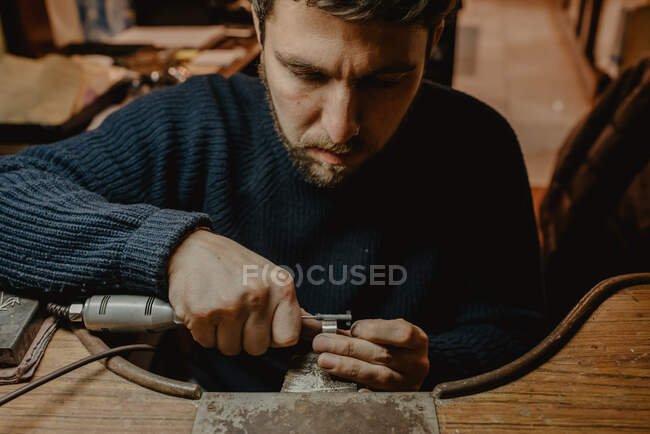 Руки ювелира-мужчины используют ручной инструмент для формирования металлического кольца в мастерской — стоковое фото